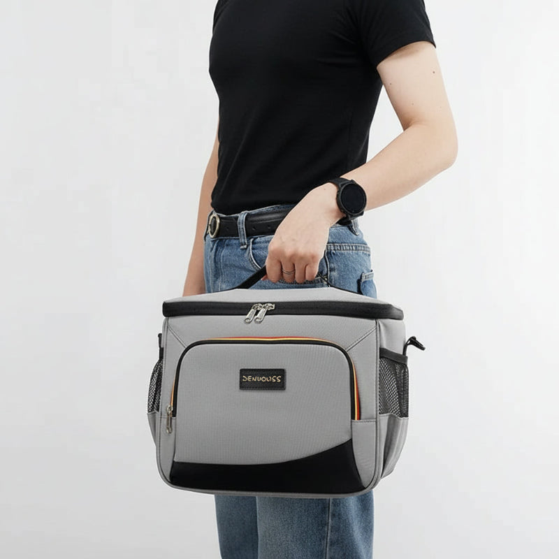 Personne tenant un sac isotherme repas gris par la poignée, vue de profil, sur fond blanc.