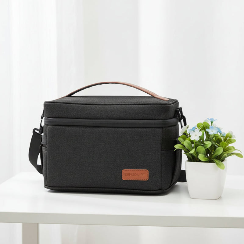 Sac isotherme repas noir avec poignée et bandoulière, posé sur une table blanche, format pratique pour transporter un déjeuner au quotidien