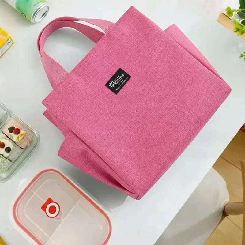 Sac isotherme rose vu de dessus posé sur une table avec boîtes repas et aliments autour