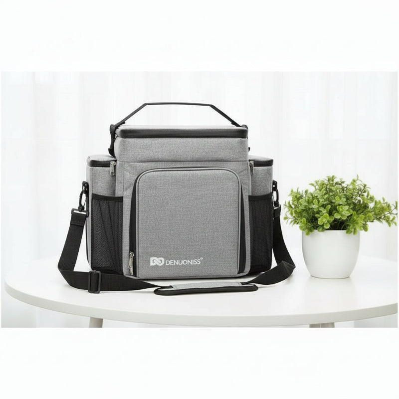 Sac pique-nique isotherme 27L gris posé sur une table, avec une plante décorative à côté.