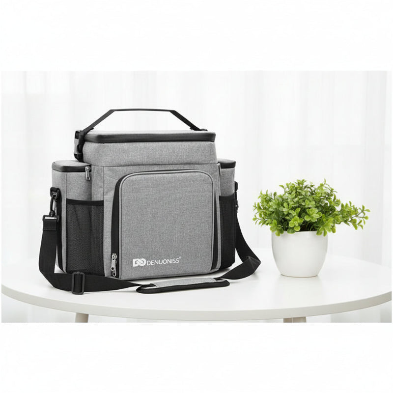 Sac pique-nique isotherme 27L gris posé sur une table, avec une plante décorative en arrière-plan.
