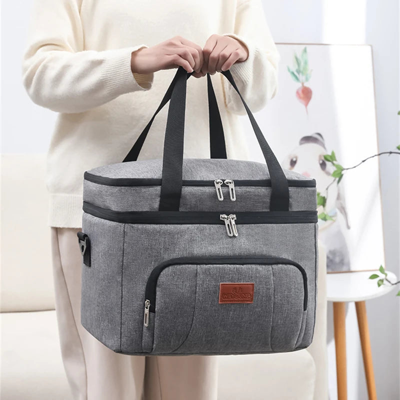 Sac repas isotherme gris à double compartiment porté à la main, idéal pour emporter repas et boissons au bureau ou en sortie.