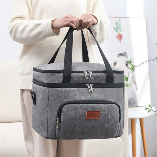 Sac repas isotherme gris à double compartiment porté à la main, idéal pour emporter repas et boissons au bureau ou en sortie.